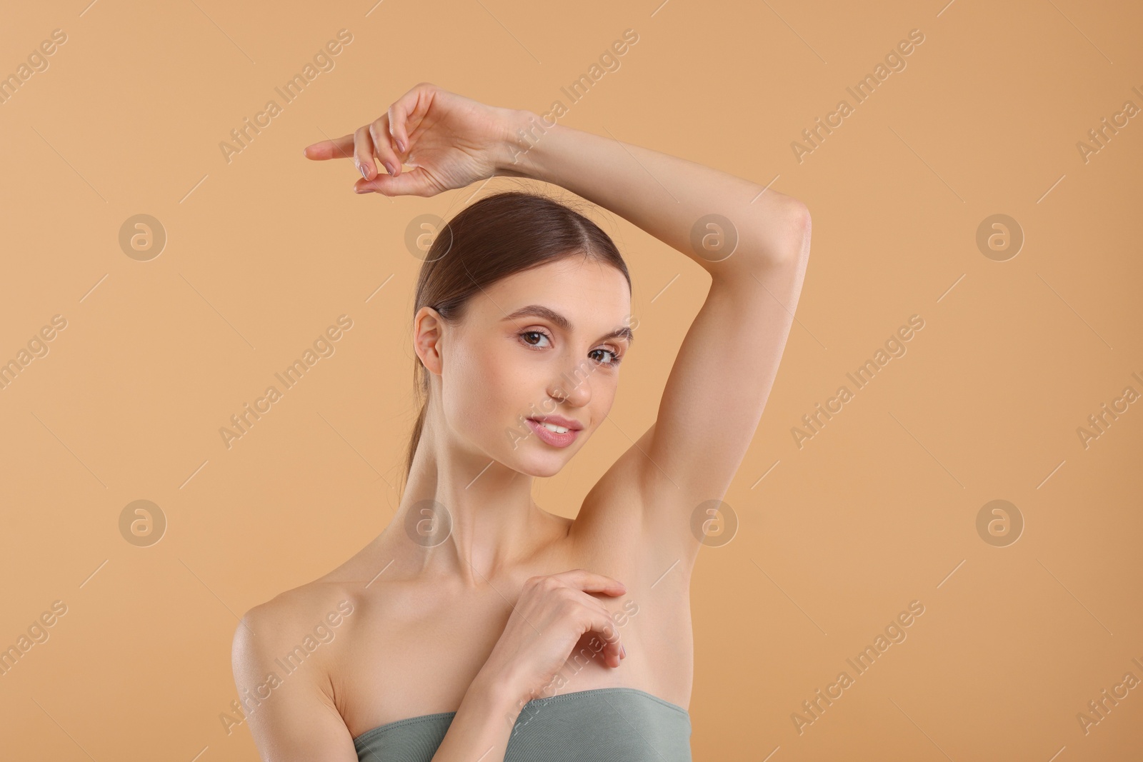 Photo of Young woman showing smooth skin after epilation on beige background