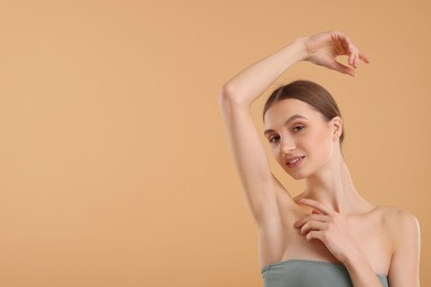 Photo of Young woman showing smooth skin after epilation on beige background, space for text