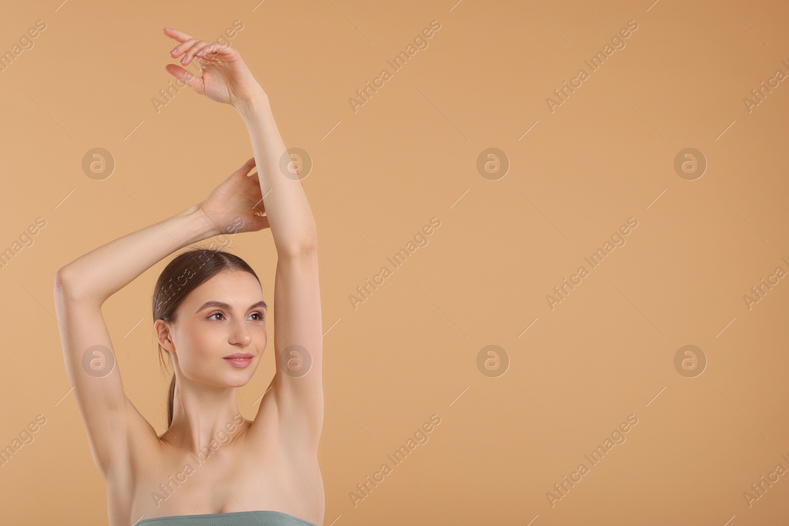 Photo of Young woman showing smooth skin after epilation on beige background, space for text