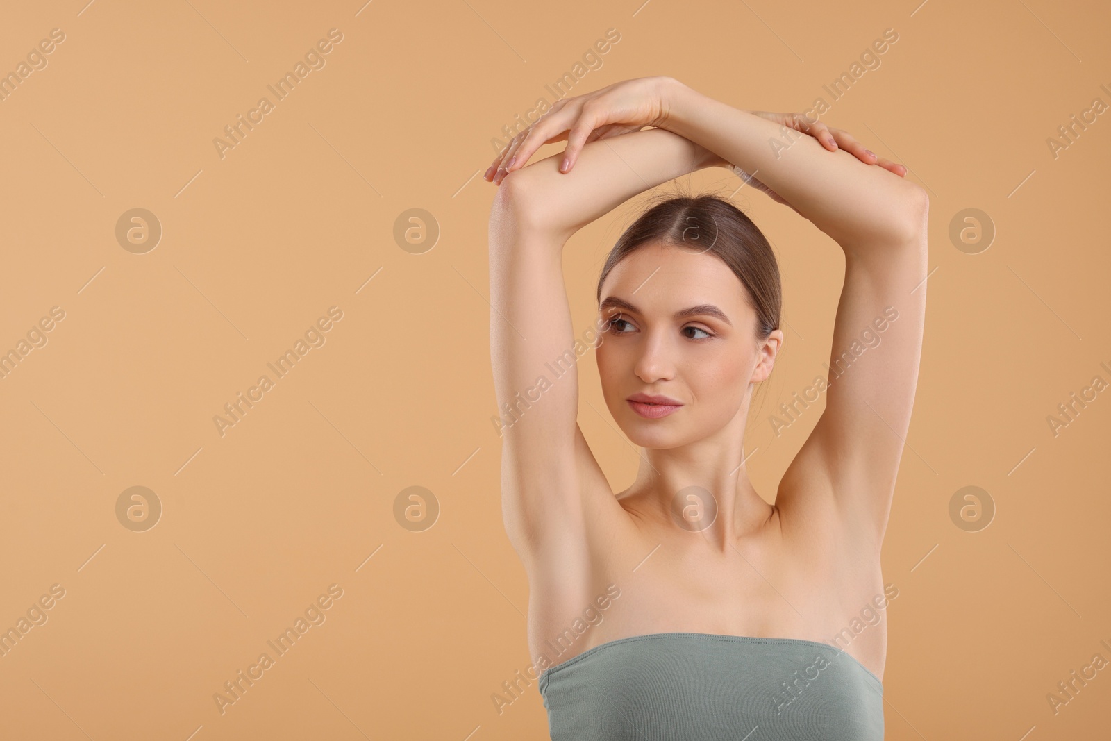 Photo of Young woman showing smooth skin after epilation on beige background, space for text