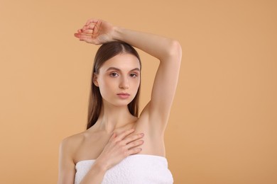 Young woman showing smooth skin after epilation on beige background