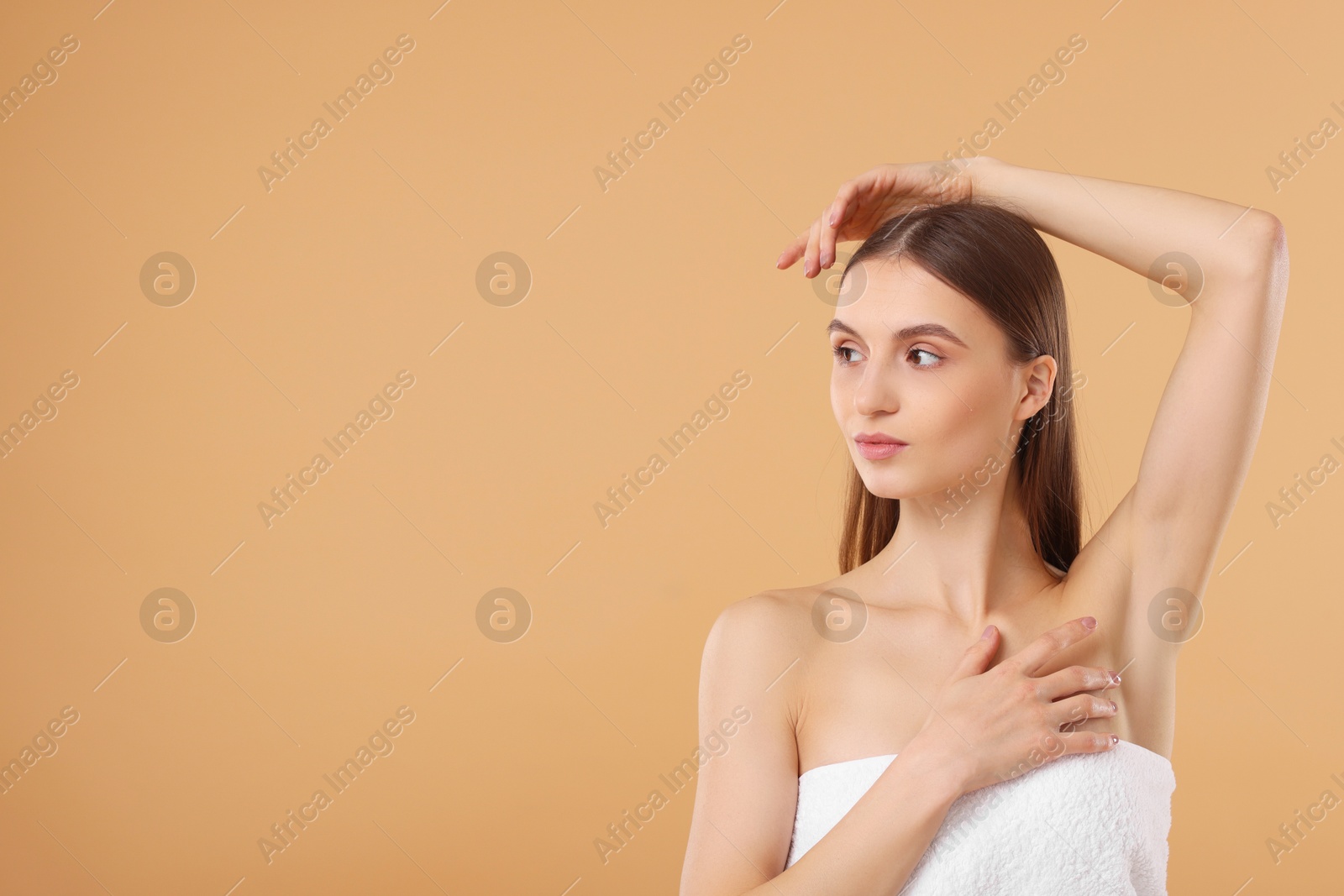 Photo of Young woman showing smooth skin after epilation on beige background, space for text