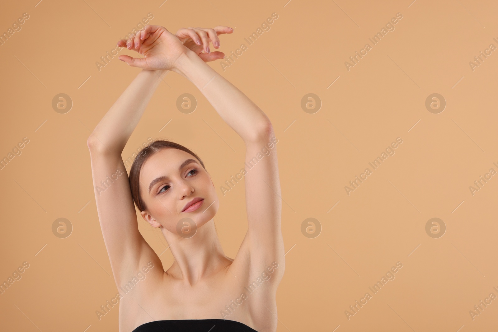 Photo of Young woman showing smooth skin after epilation on beige background, space for text