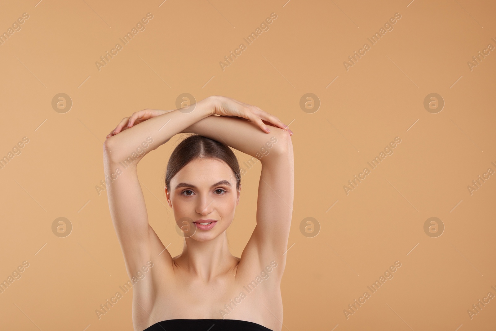 Photo of Young woman showing smooth skin after epilation on beige background, space for text