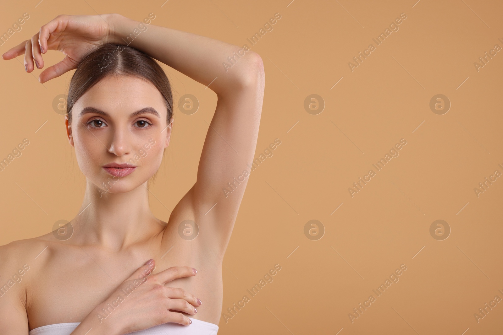 Photo of Young woman showing smooth skin after epilation on beige background, space for text