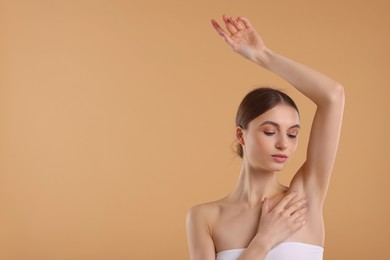 Young woman showing smooth skin after epilation on beige background, space for text