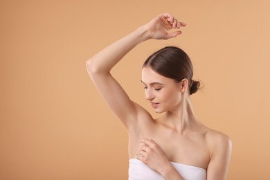 Photo of Young woman showing smooth skin after epilation on beige background