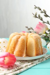 Photo of Delicious bundt cake, Easter eggs, willow branches and tulips on light blue wooden table