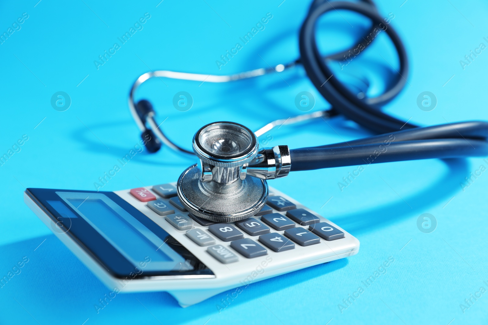 Stethoscope and calculator on light blue background, closeup Photo of Stethoscope and calculator on light blue background, closeup