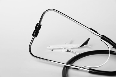 Photo of Stethoscope and airplane model on light background, closeup