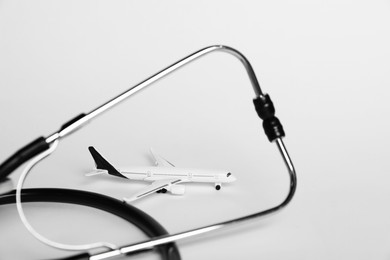 Photo of Stethoscope and airplane model on light background, closeup