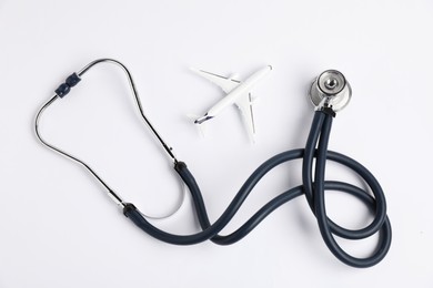 Photo of Stethoscope and airplane model on light background, flat lay