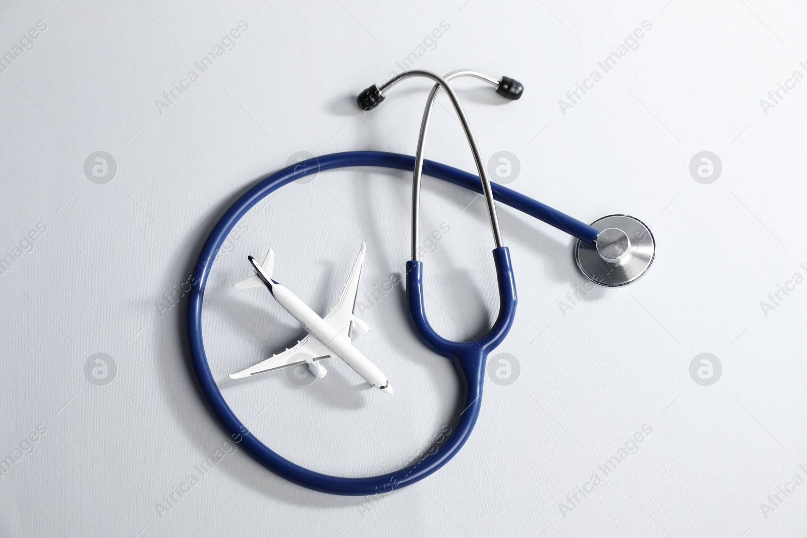 Stethoscope and airplane model on light background, flat lay Photo of Stethoscope and airplane model on light background, flat lay
