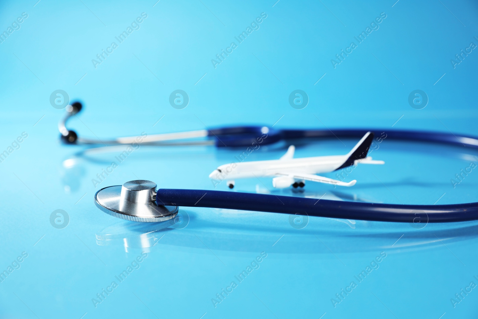 Stethoscope and airplane model on light blue background, closeup Photo of Stethoscope and airplane model on light blue background, closeup