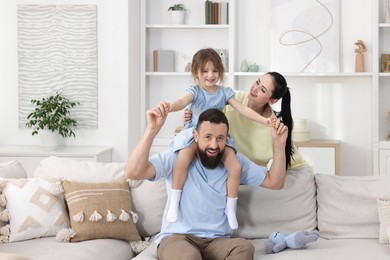 Photo of Cute little girl and her parents having fun at home