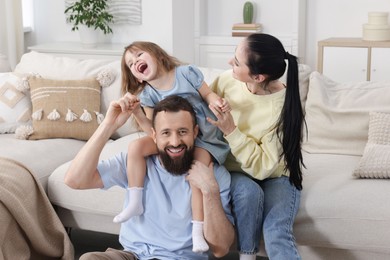 Photo of Cute little girl and her parents having fun at home