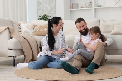 Photo of Cute little girl and her parents having fun at home