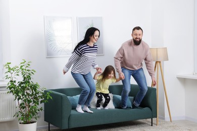 Cute little girl and her parents having fun at home