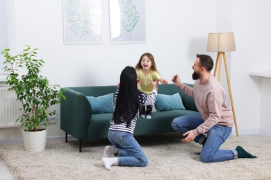 Photo of Cute little girl and her parents having fun at home