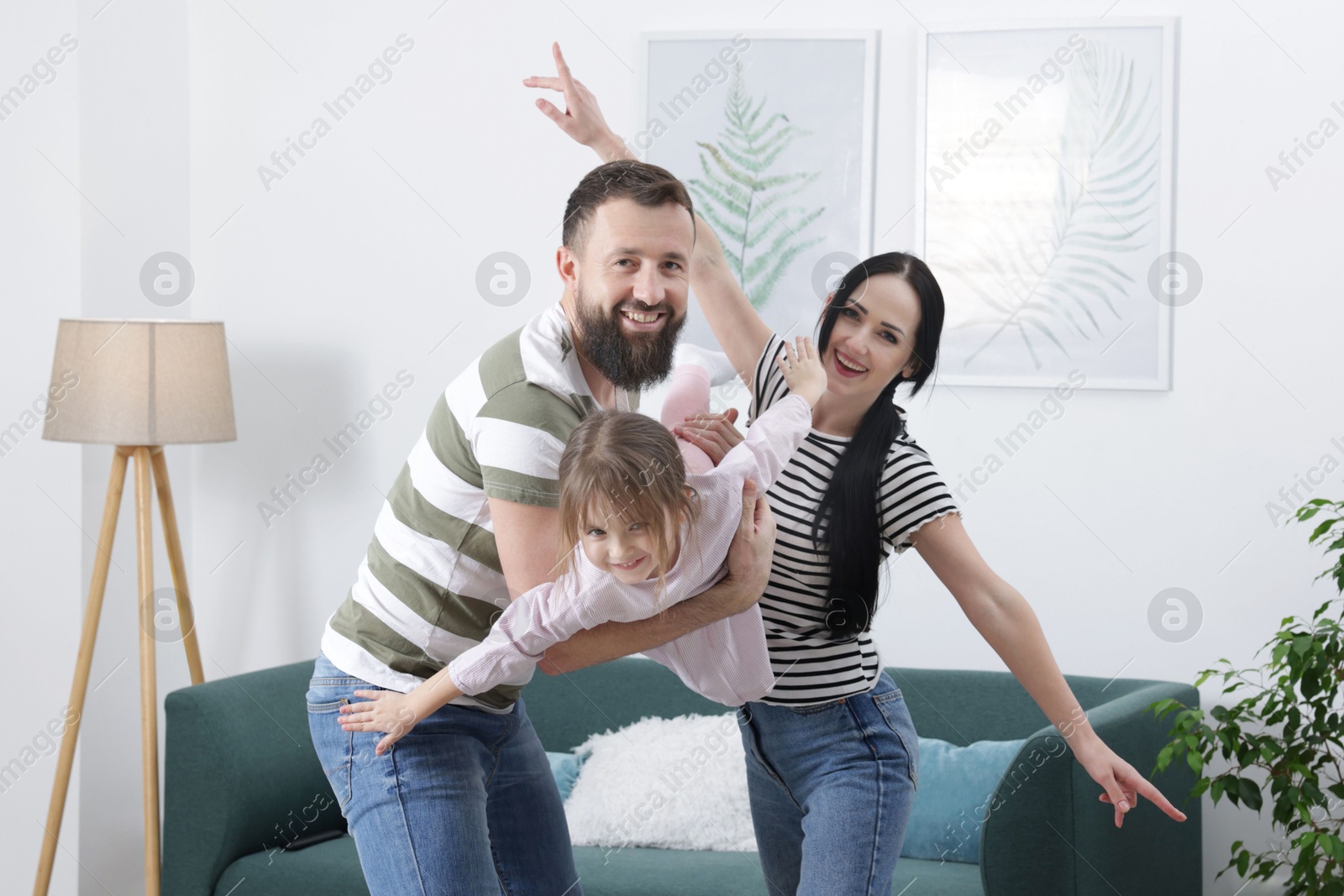 Photo of Cute little girl and her parents having fun at home