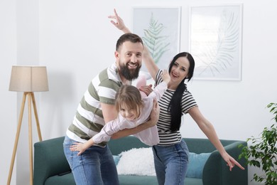 Photo of Cute little girl and her parents having fun at home