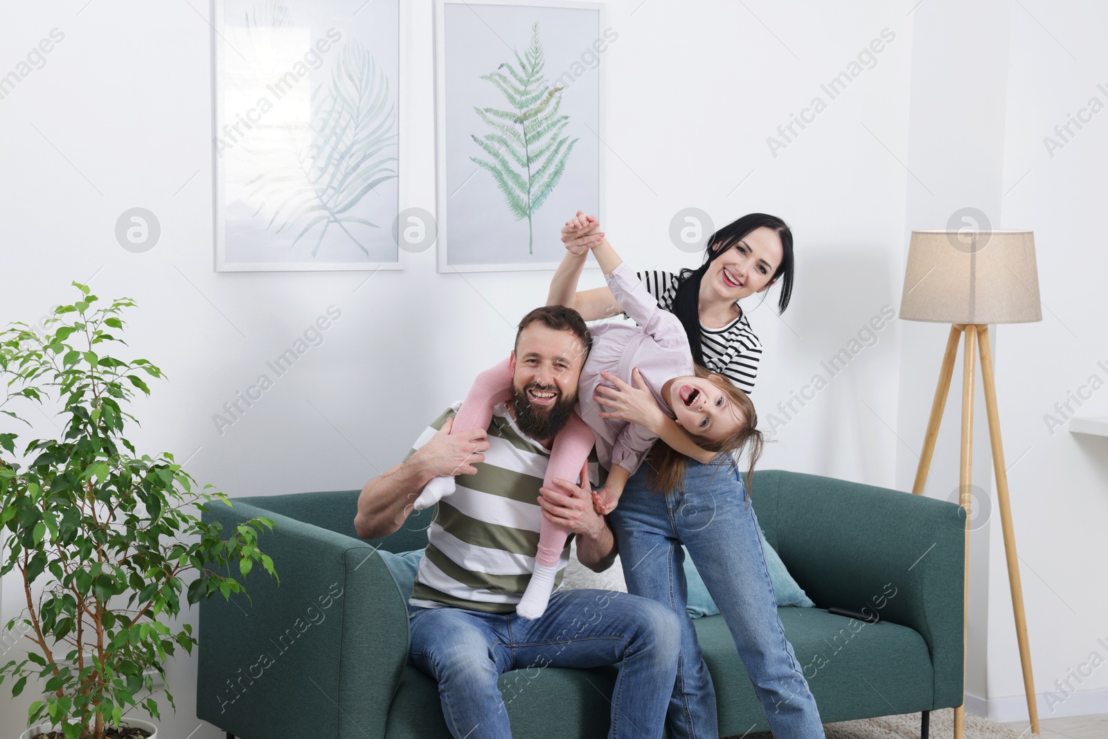 Photo of Cute little girl and her parents having fun at home