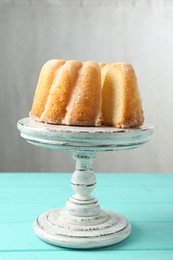 Photo of Delicious bundt cake on light blue wooden table against gray background