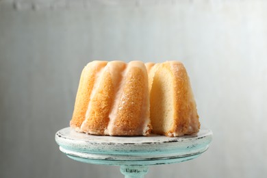 Photo of Delicious bundt cake on stand against gray background