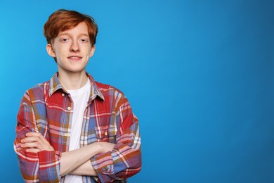 Smiling teenage boy with freckles on light blue background. Space for text