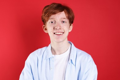 Photo of Smiling teenage boy with freckles on red background