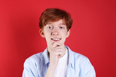 Smiling teenage boy with freckles on red background