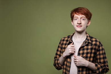 Photo of Portrait of smiling teenage boy with freckles on dark green background. Space for text