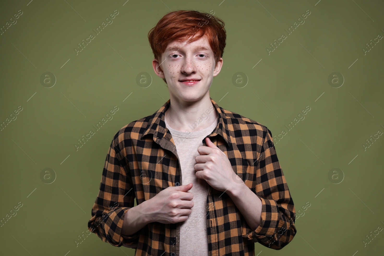 Photo of Portrait of smiling teenage boy with freckles on dark green background