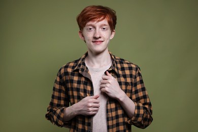 Portrait of smiling teenage boy with freckles on dark green background