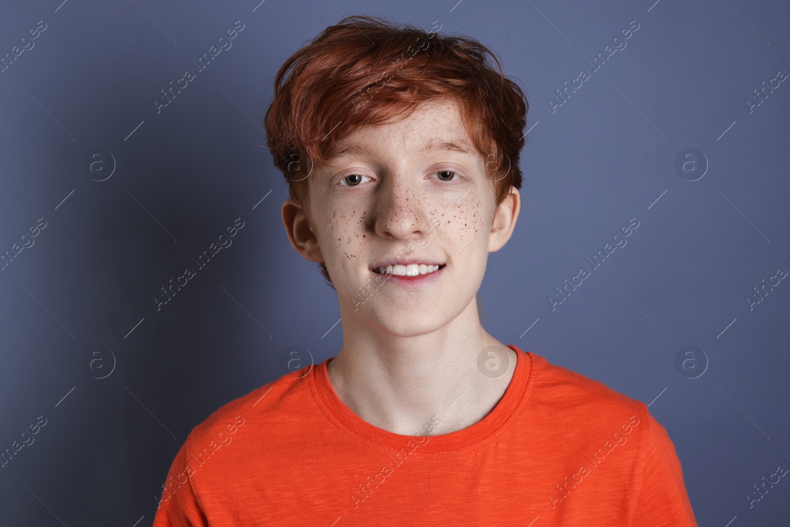 Photo of Smiling teenage boy with freckles on grey background