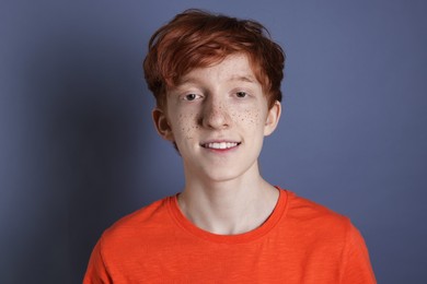 Photo of Smiling teenage boy with freckles on grey background