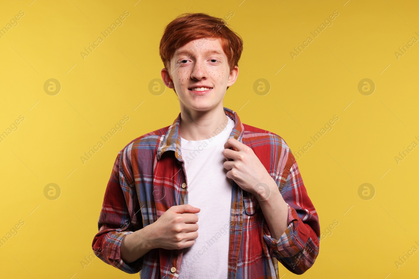 Photo of Portrait of smiling teenage boy with freckles on yellow background