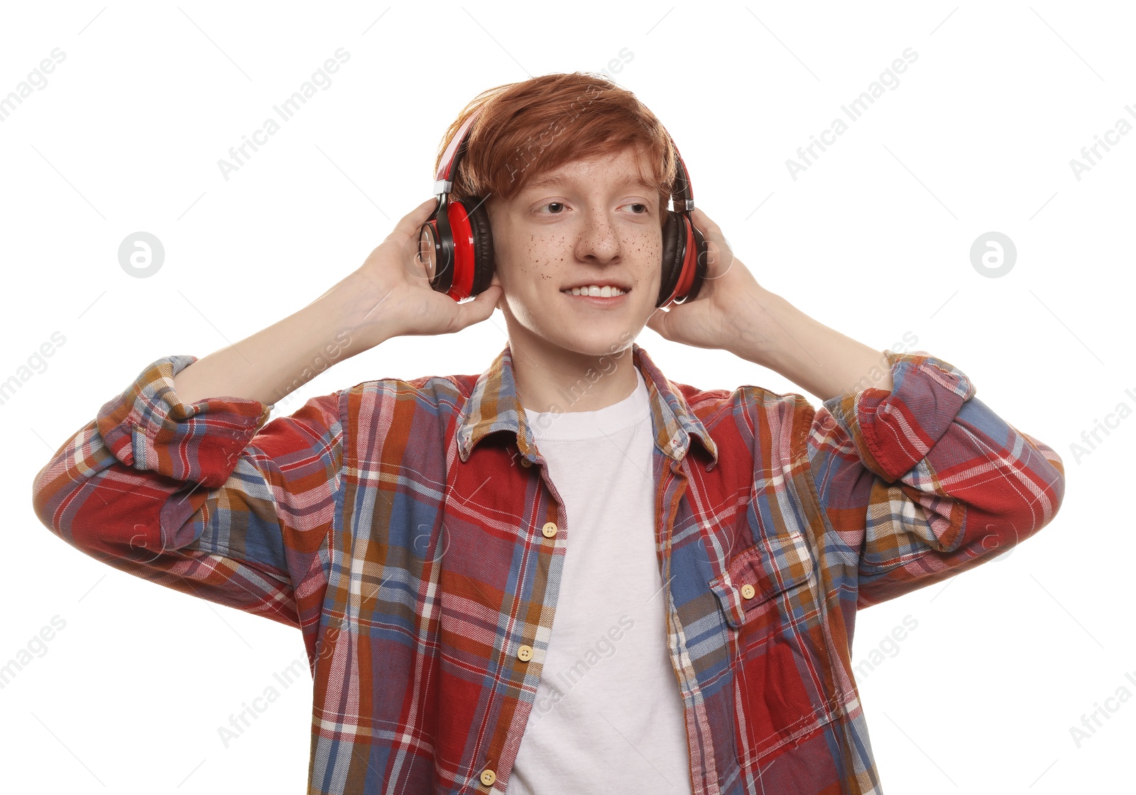 Photo of Smiling teenage boy with freckles listening to music by headphones on white background