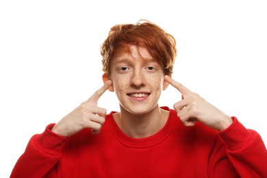 Smiling teenage boy pointing at his freckles on white background