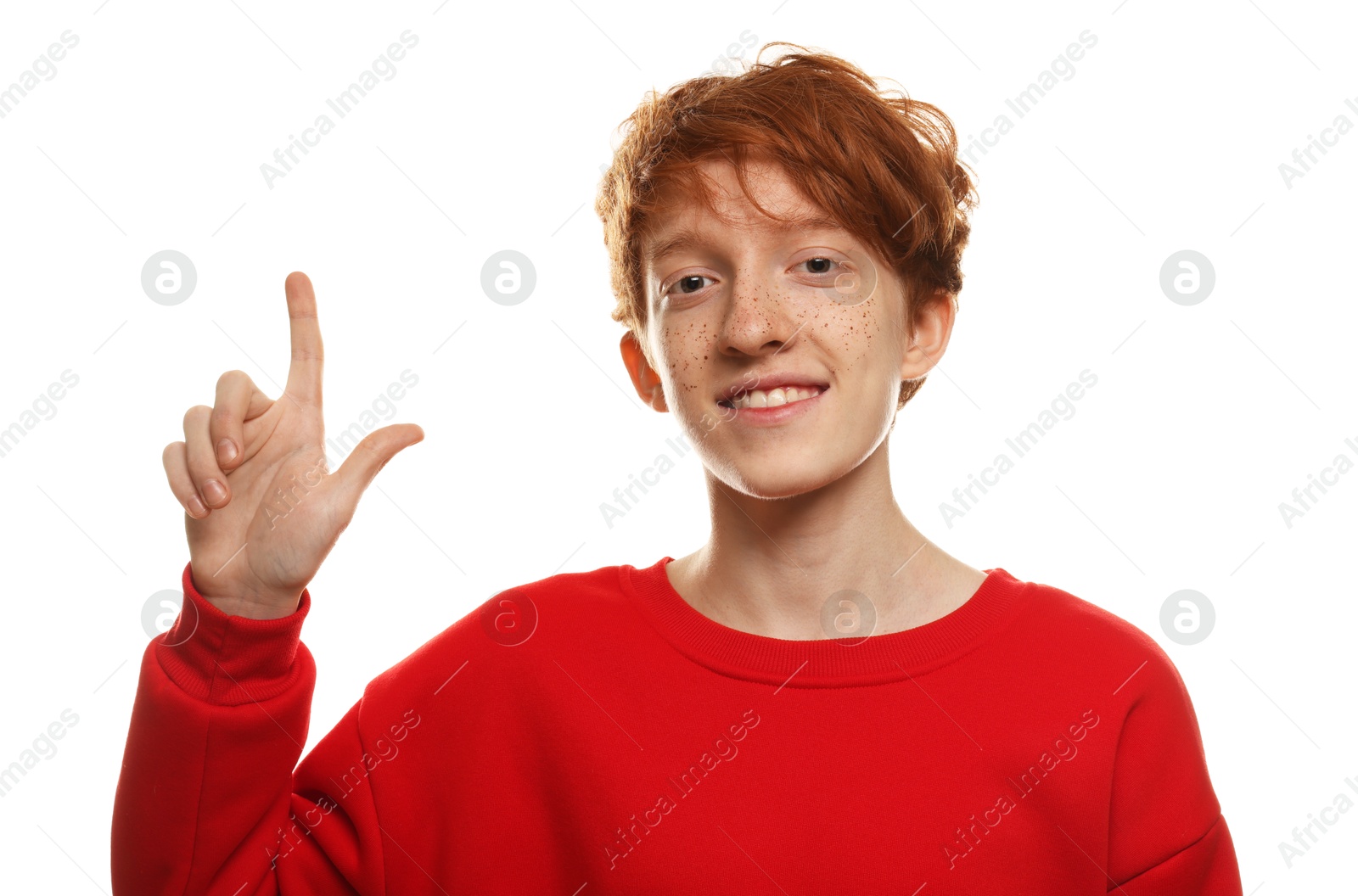 Photo of Smiling teenage boy with freckles pointing upwards on white background