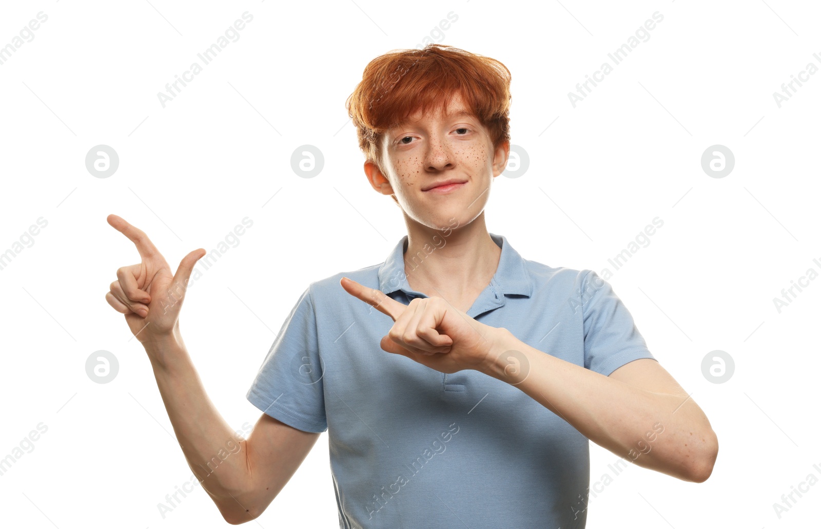 Photo of Cute teenage boy with freckles pointing at something on white background