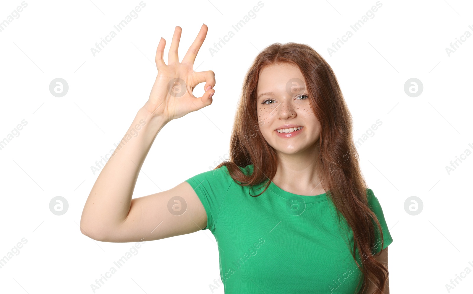 Photo of Beautiful teenage girl with freckles showing OK gesture on white background