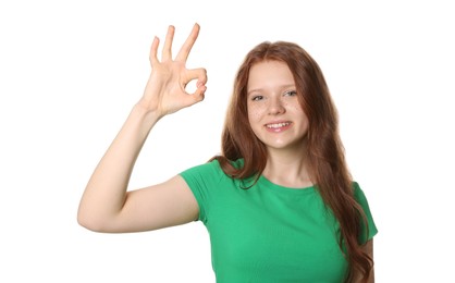 Photo of Beautiful teenage girl with freckles showing OK gesture on white background