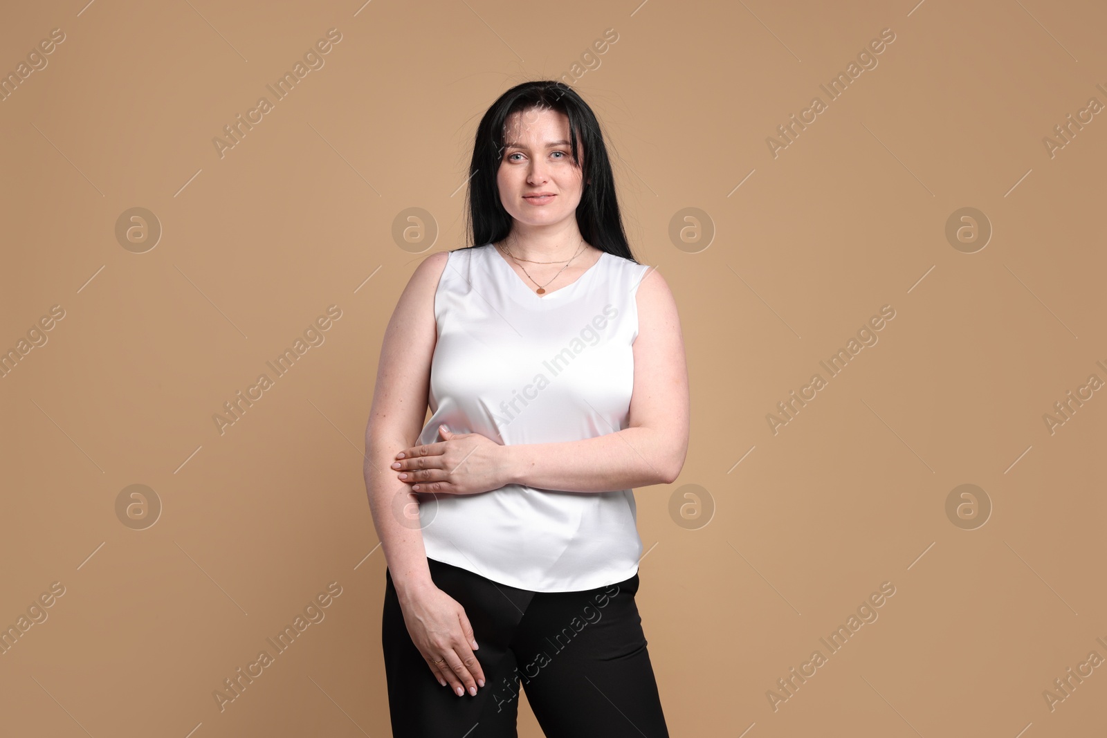 Photo of Portrait of charming plus size model on beige background. Overweight