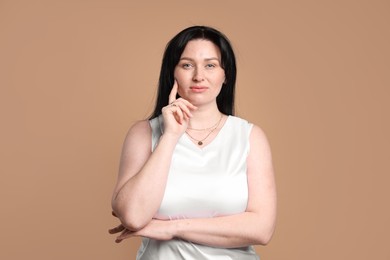 Portrait of charming plus size model on beige background. Overweight