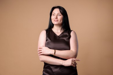 Photo of Portrait of smiling plus size model on beige background. Overweight