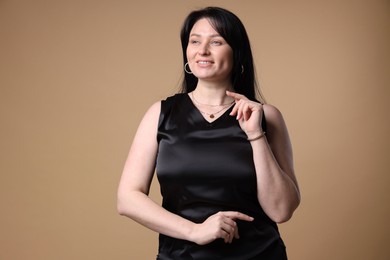 Portrait of smiling plus size model on beige background. Overweight