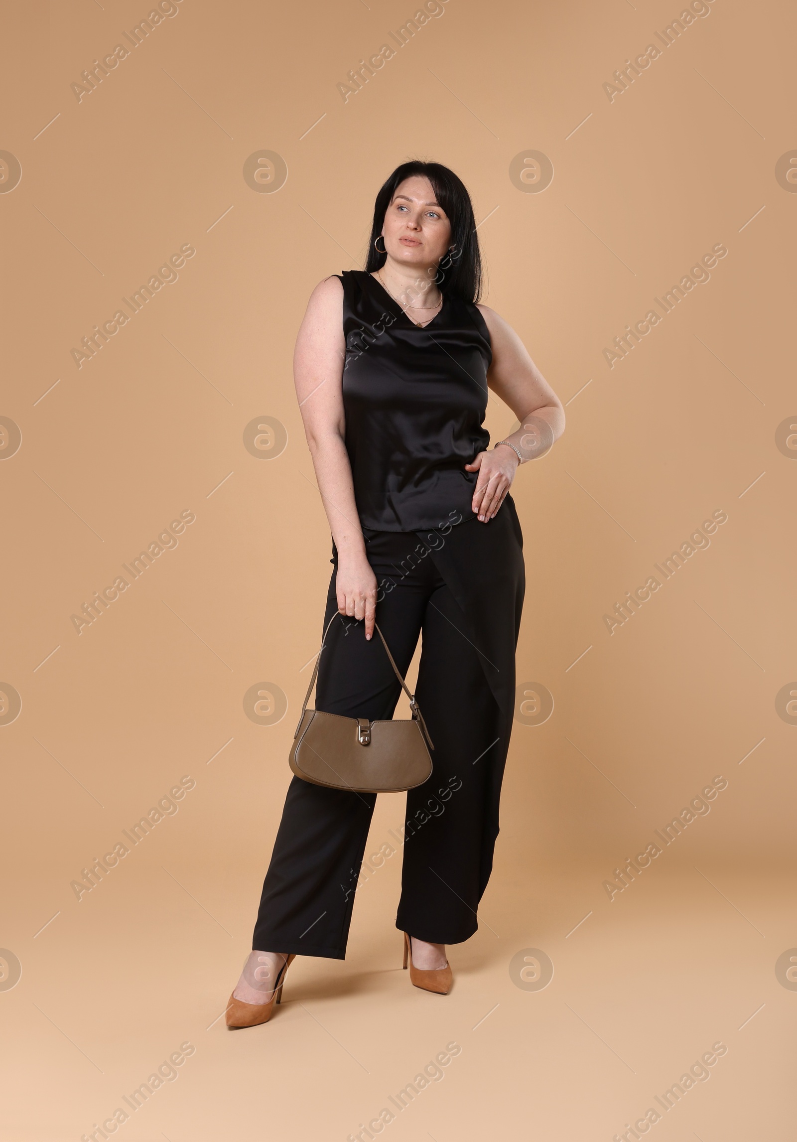 Photo of Elegant plus size model with bag on beige background. Overweight