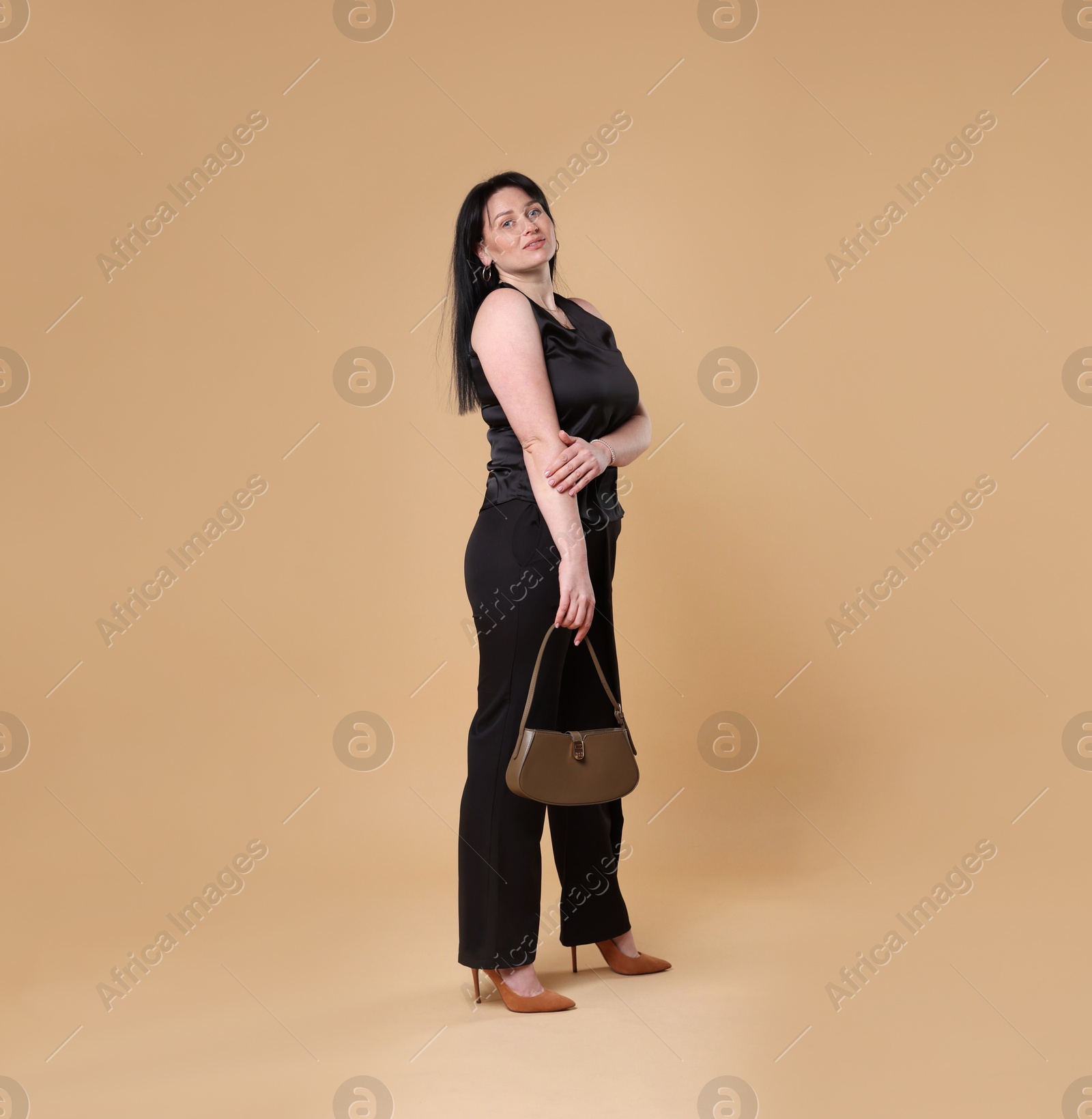 Photo of Elegant plus size model with bag on beige background. Overweight