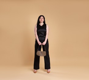 Elegant plus size model with bag on beige background. Overweight